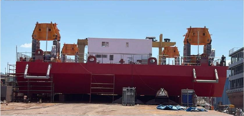 Side view of the red BROS J900 jack-up barge at the shipyard